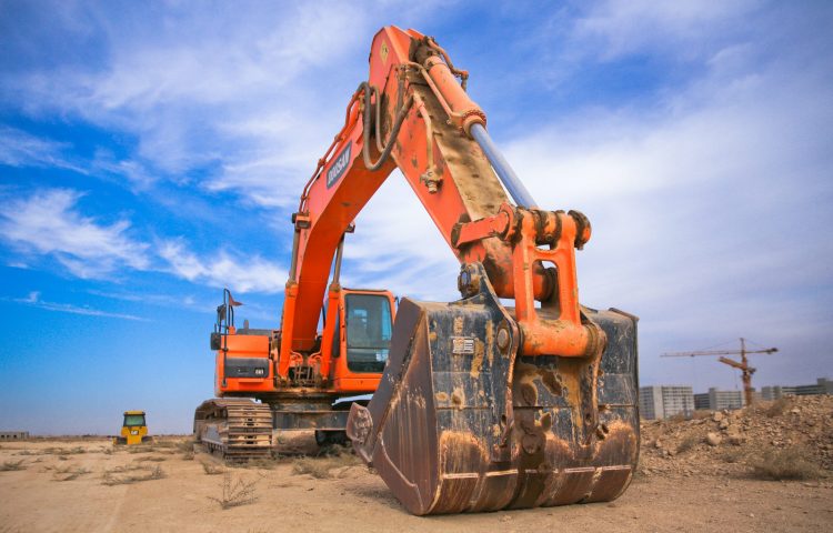 orange-excavator-under-white-clouds